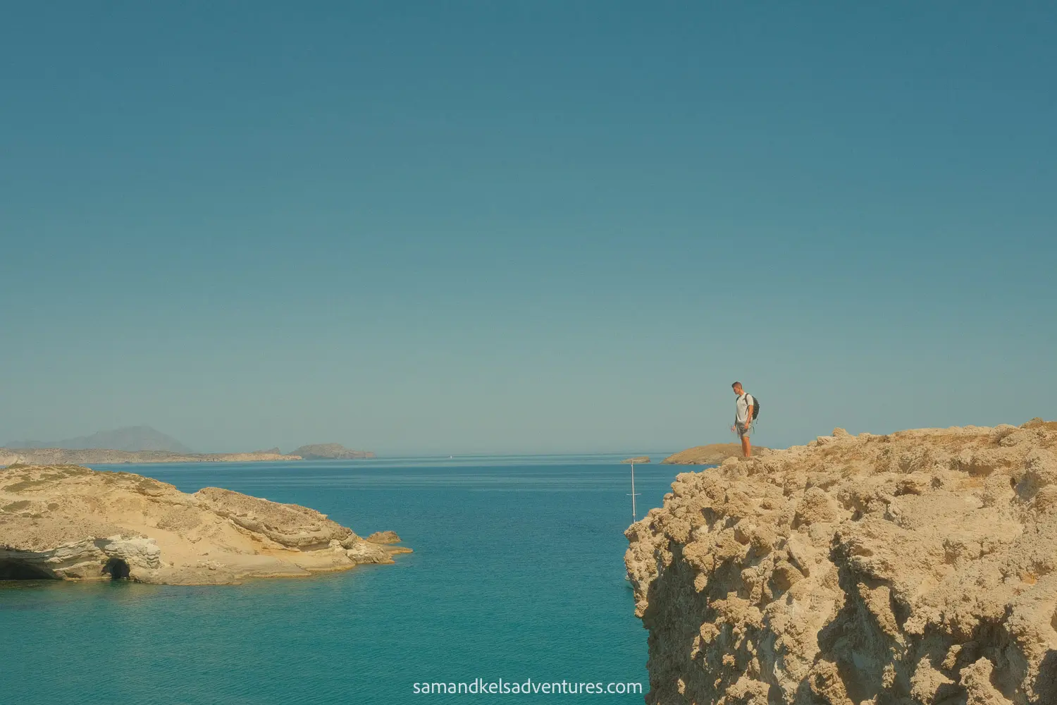 things to do in milos sam standing on the ledge with the views in the background