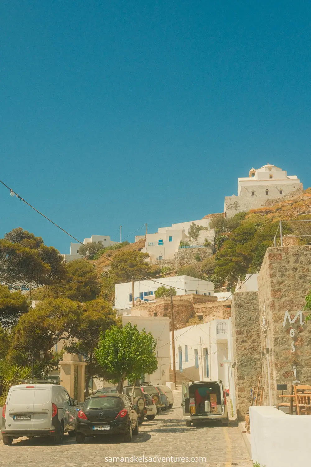 things to do in milos white buildings with cars in the foreground