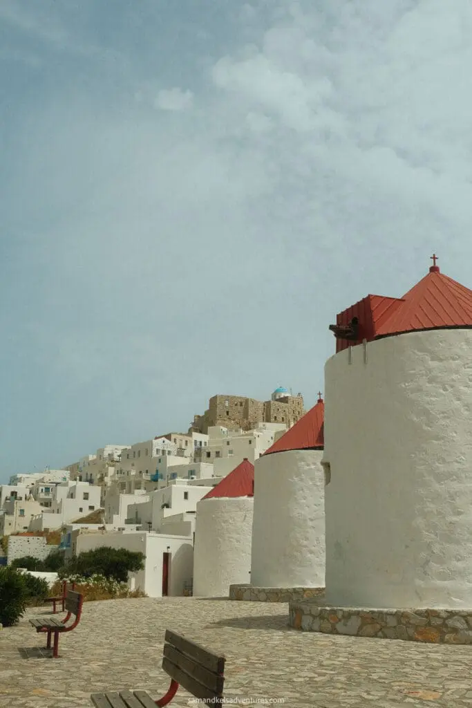 things to do in astypalaia white and red windmills with town and benches