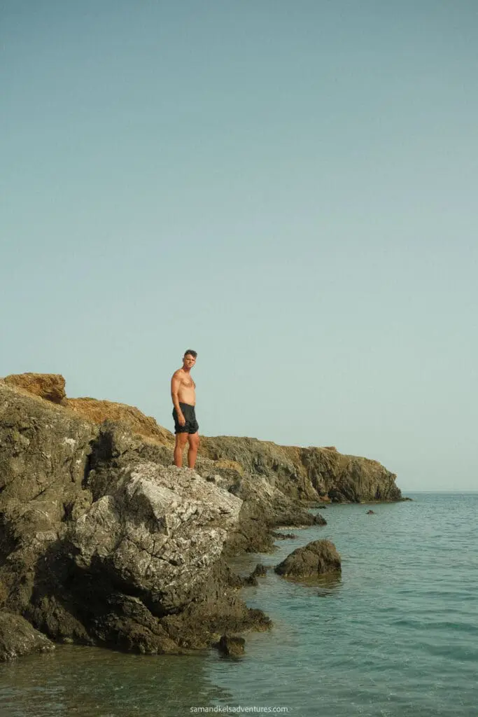 traveling to greece tips standing on rock on ocean