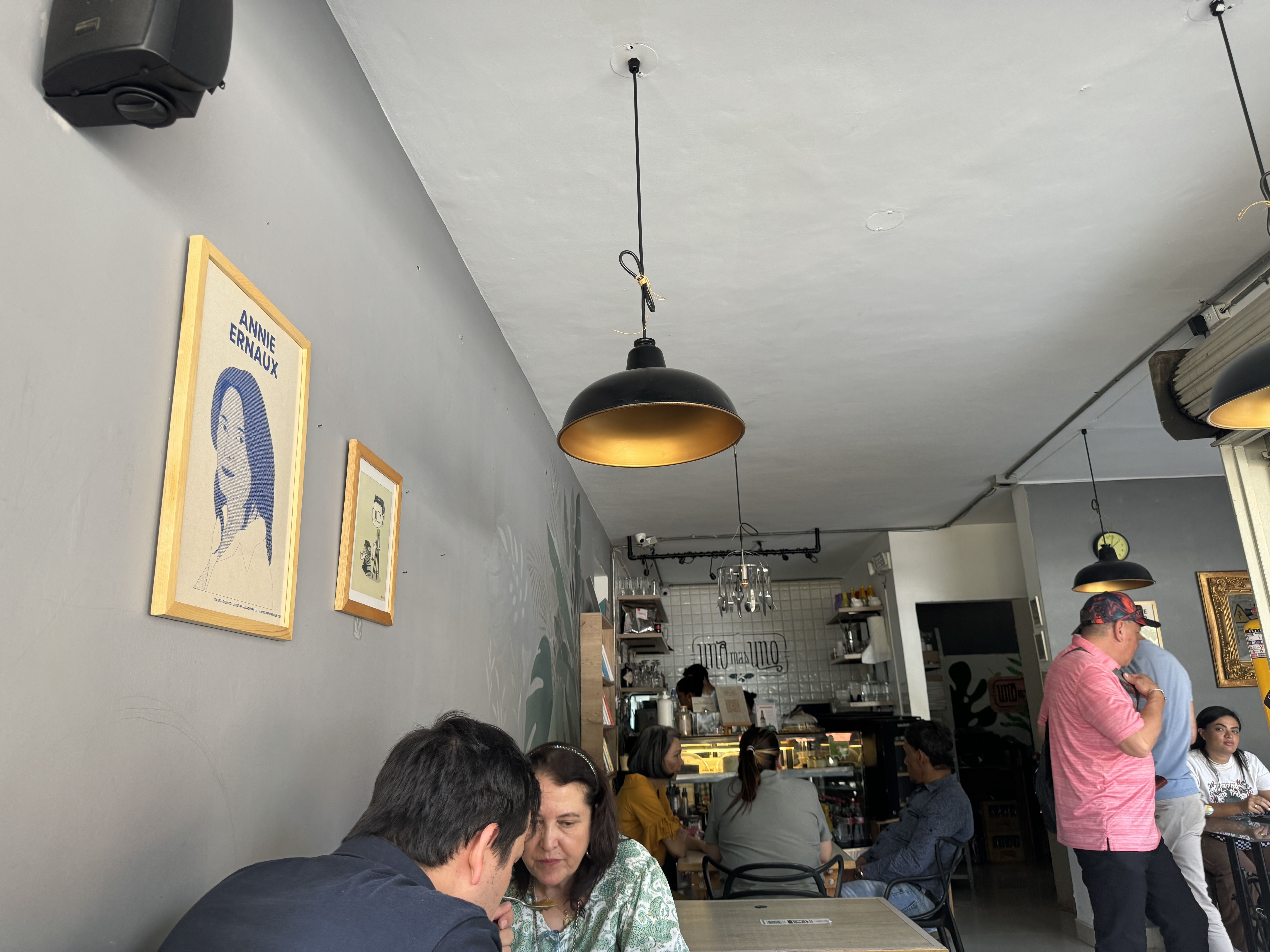 Interior of the cafe and lunch restaurant Uno mas Uno with tables a bar and people eating their food