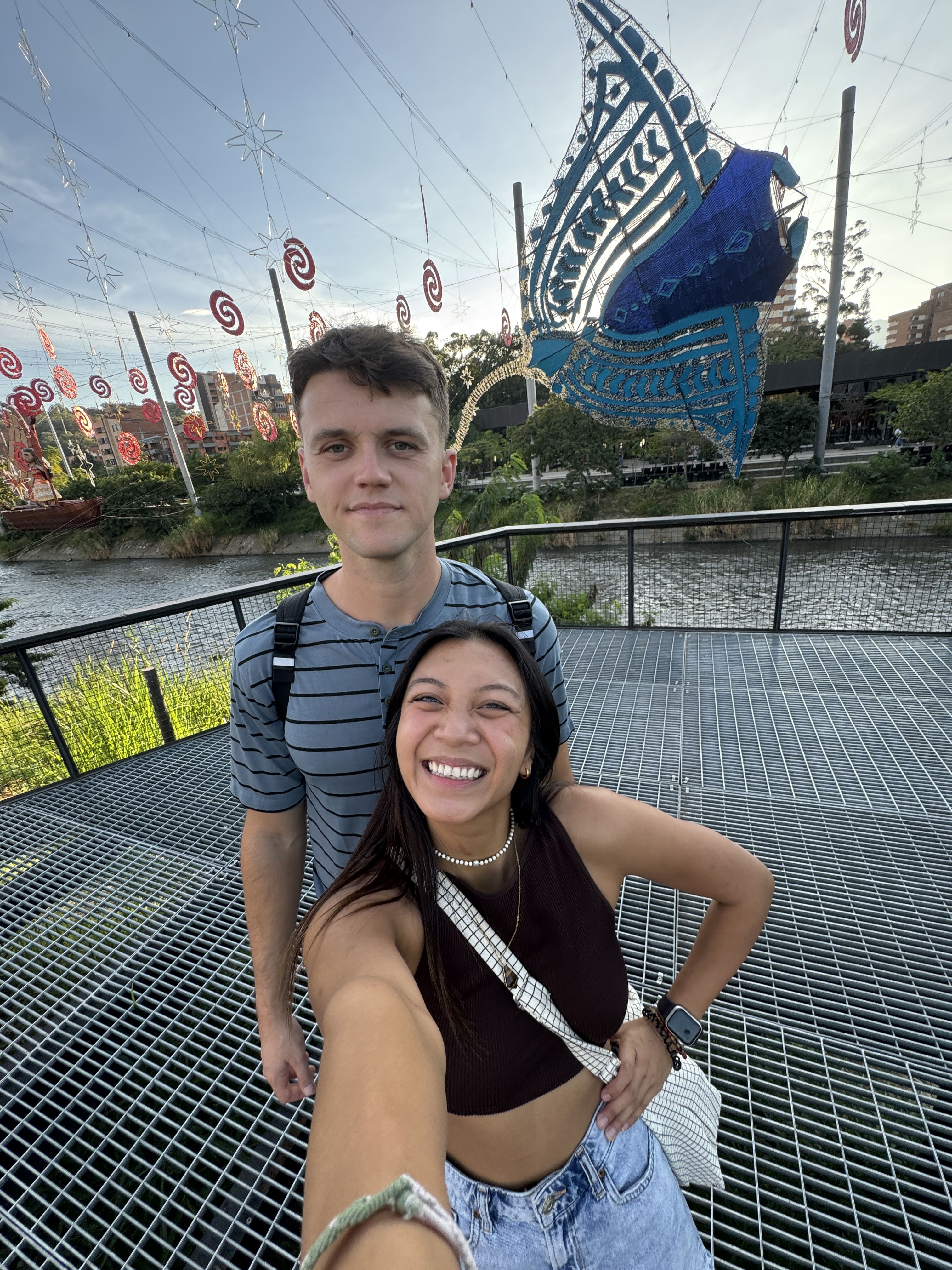 Selfie couple posing in front of the riverwalk with a stingray in the background